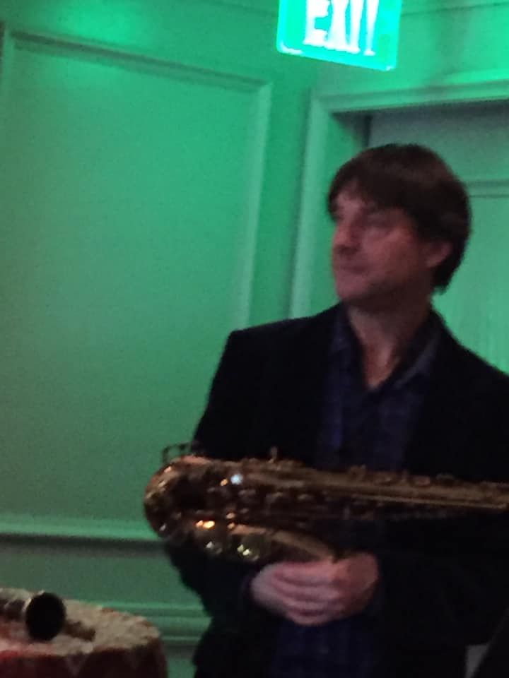 Dan with the alto sax under green stage light